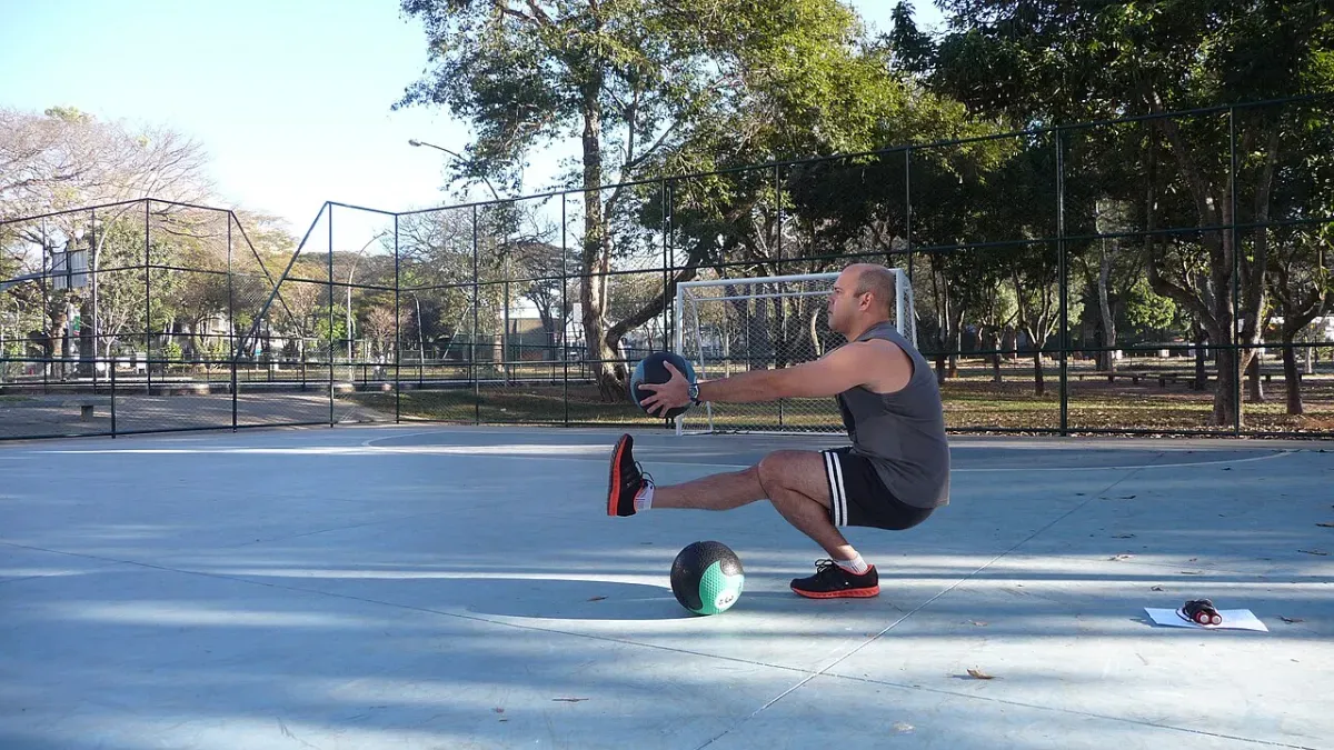 Uomo che esegue un pistol squat, squat completo su una gamba sola