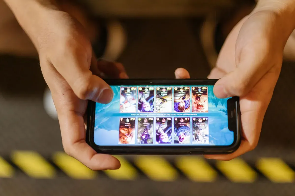 Hands holding a smartphone, playing a colorful virtual pet app game