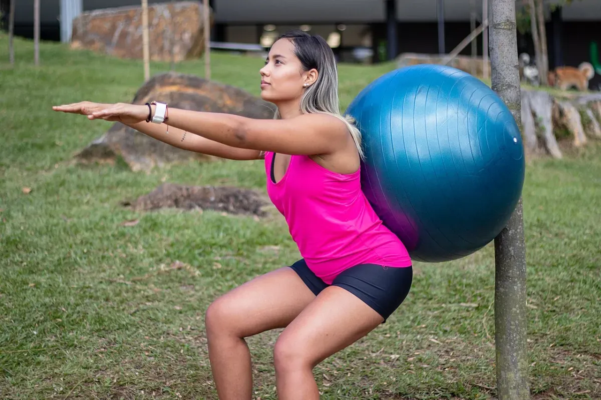 Booty workout at home: woman doing squats on a stability ball