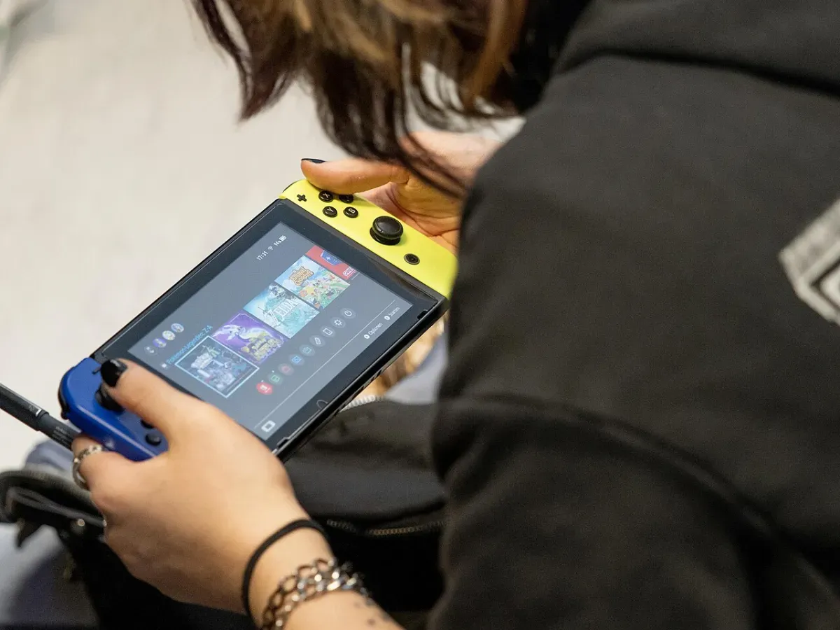 Person in a hoodie browsing games on a Nintendo Switch held in handheld mode