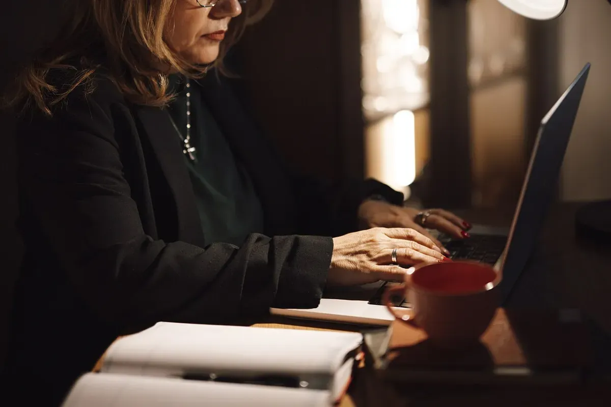 An adult typing on a laptop at home in the evening, choosing a pet game to play