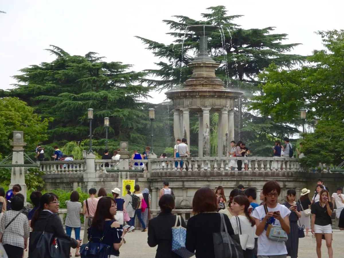 A crowd of people playing location-based games on their phones in a city park