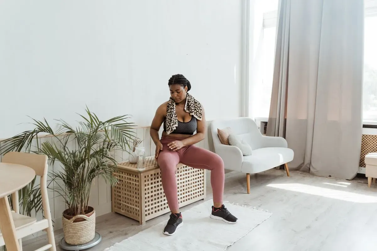 a woman doing a bodyweight workout at home in her living room, avoiding gym anxiety