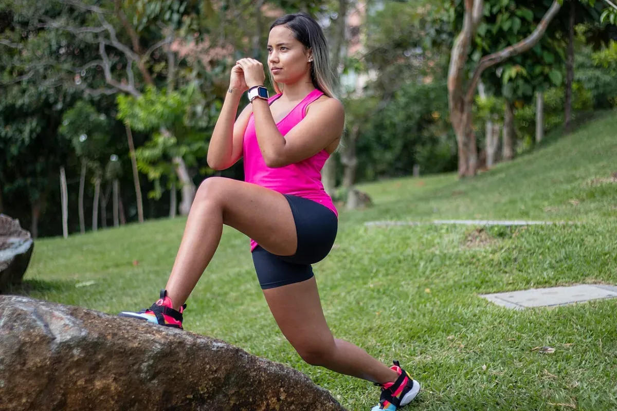 Woman in a split squat with her front foot on a rock, front knee bent to load the quad