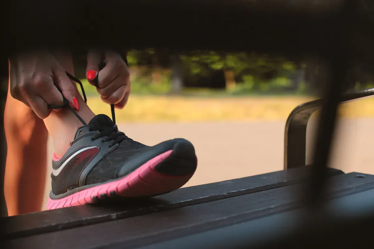 Tying running shoes on a park bench, ready to head to the gym