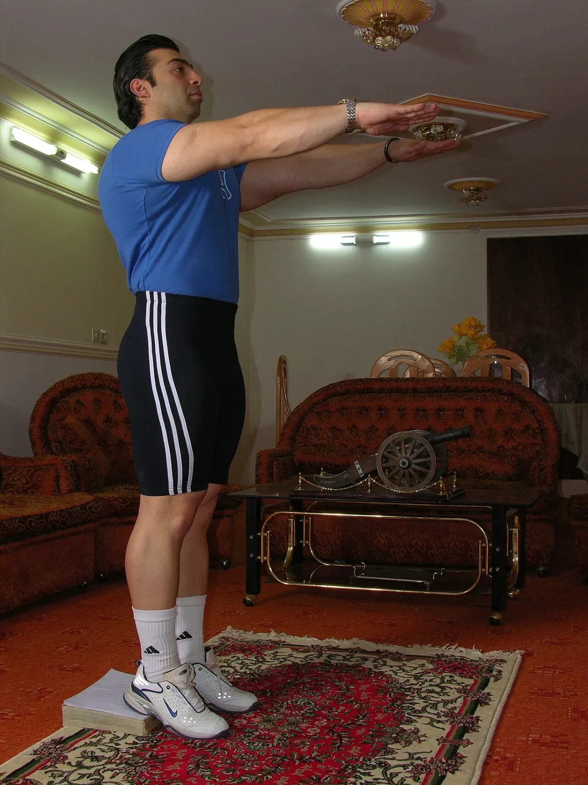 Man at the top of a bodyweight squat during a leg workout at home