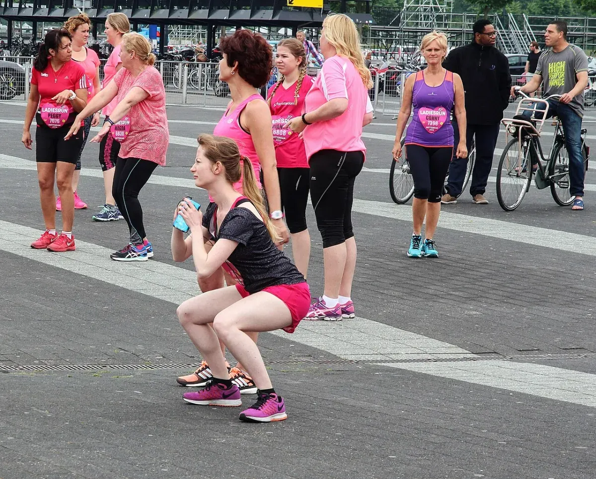 Woman doing a bodyweight squat outdoors as part of a leg workout with no equipment