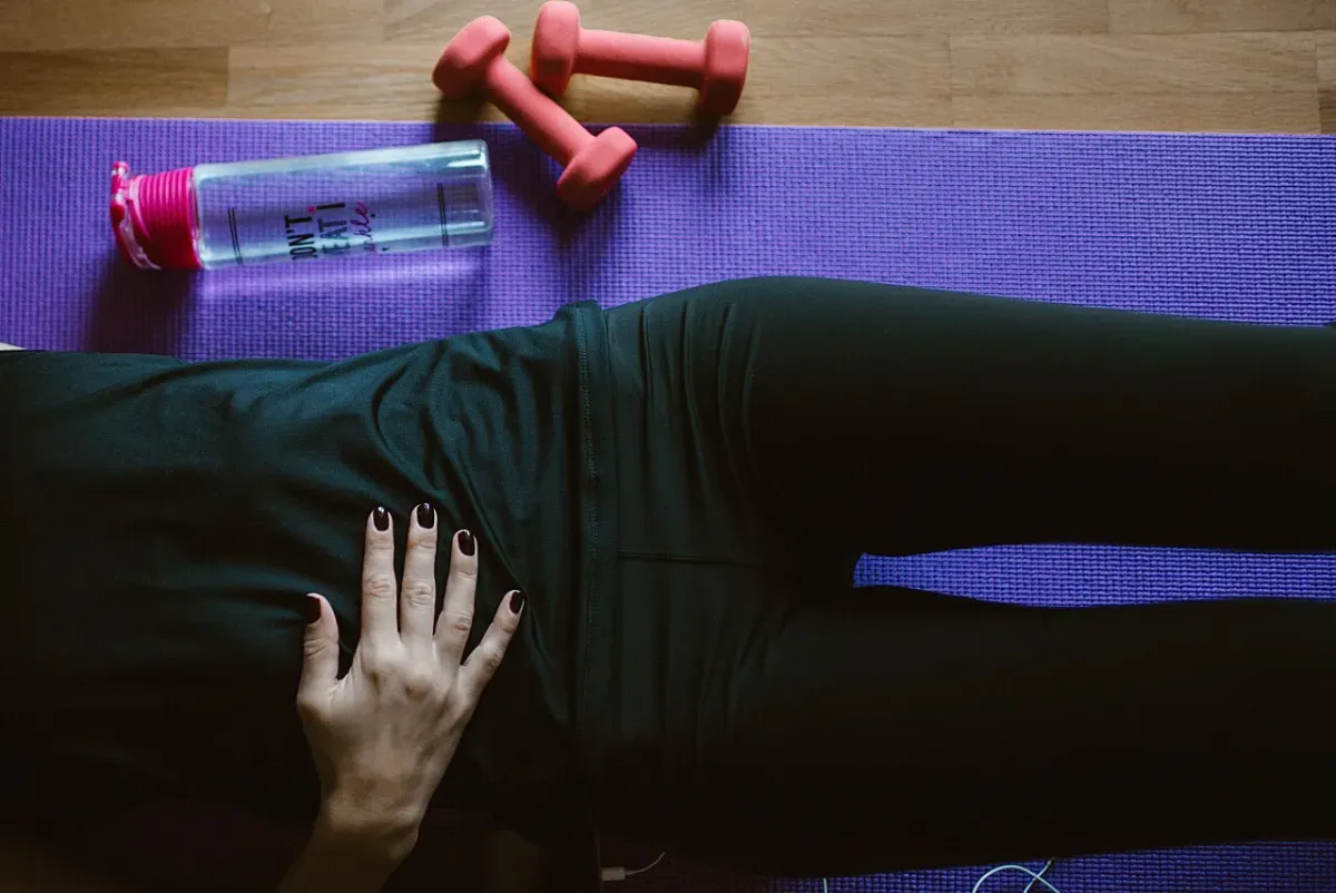 Lying on an exercise mat at home with dumbbells within reach, the floor version of a workout on a no-motivation day