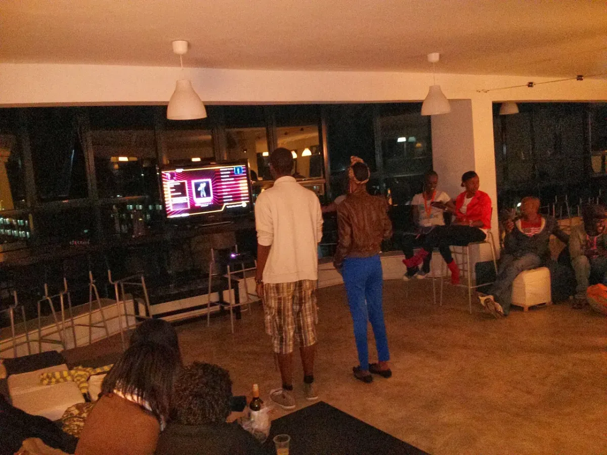 Friends dancing to Just Dance in front of a TV at an evening get-together