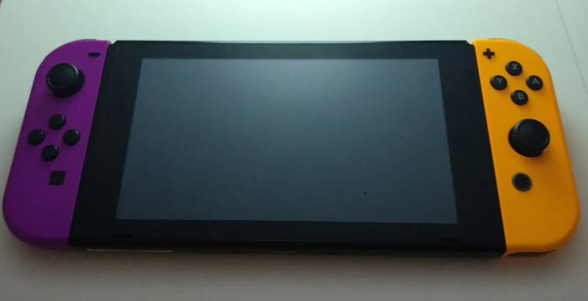 A Nintendo Switch console with purple and orange Joy-Con controllers attached