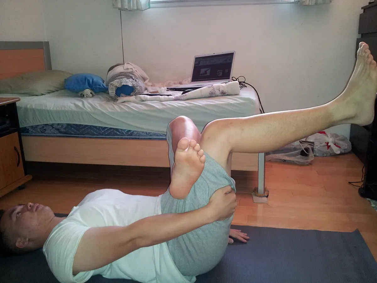 Gentle knee-to-chest stretch for sciatica relief on a yoga mat
