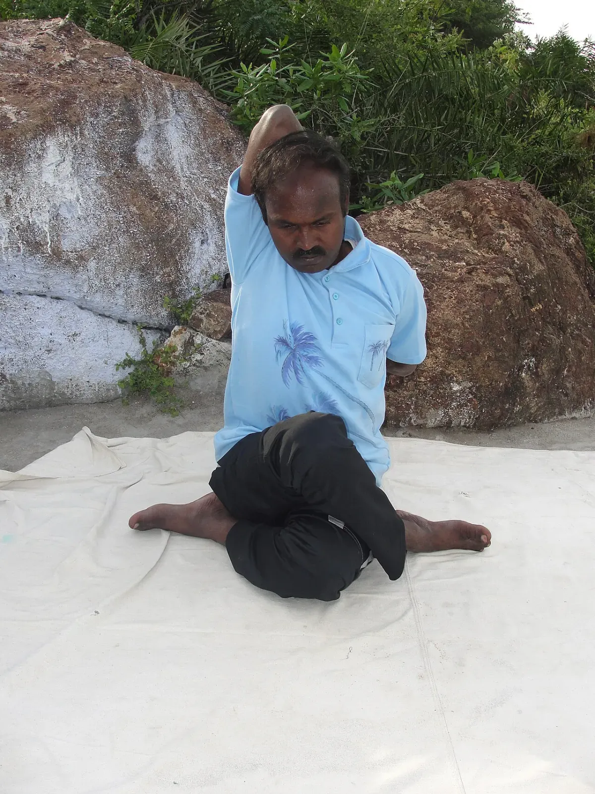 Man seated reaching one arm behind his back, a classic shoulder mobility test position