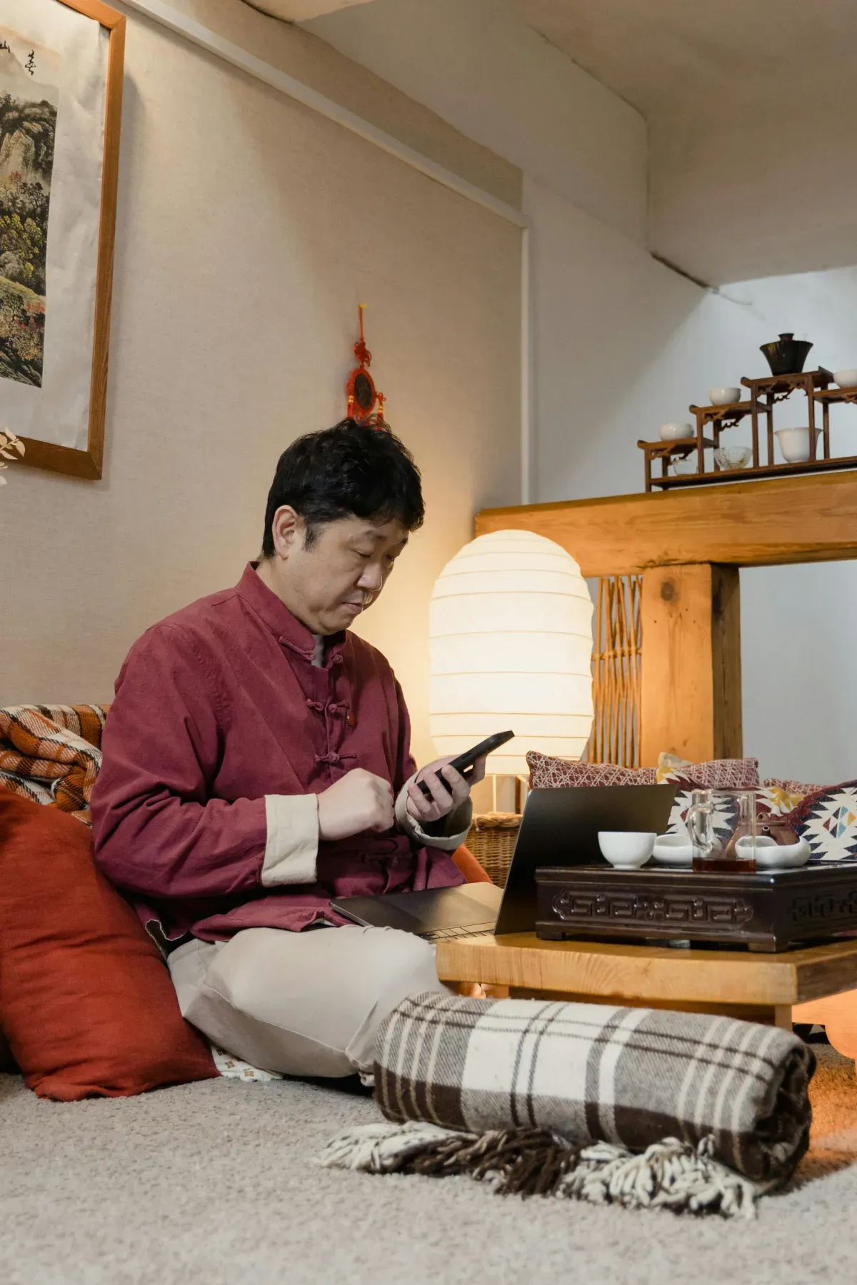 和室で座ってスマートフォンを操作する男性。落ち着いた自宅でアプリを使う様子