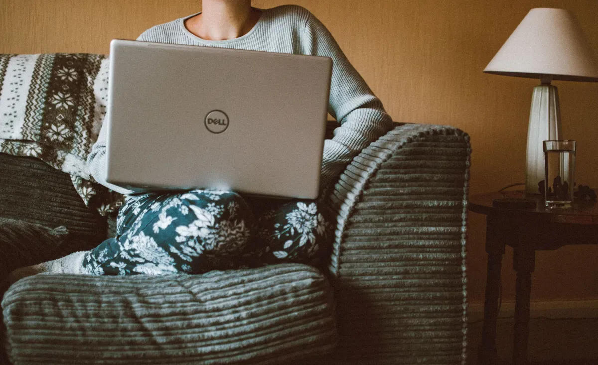 A person on a laptop in a cozy home setting, choosing between browser pets and a phone companion