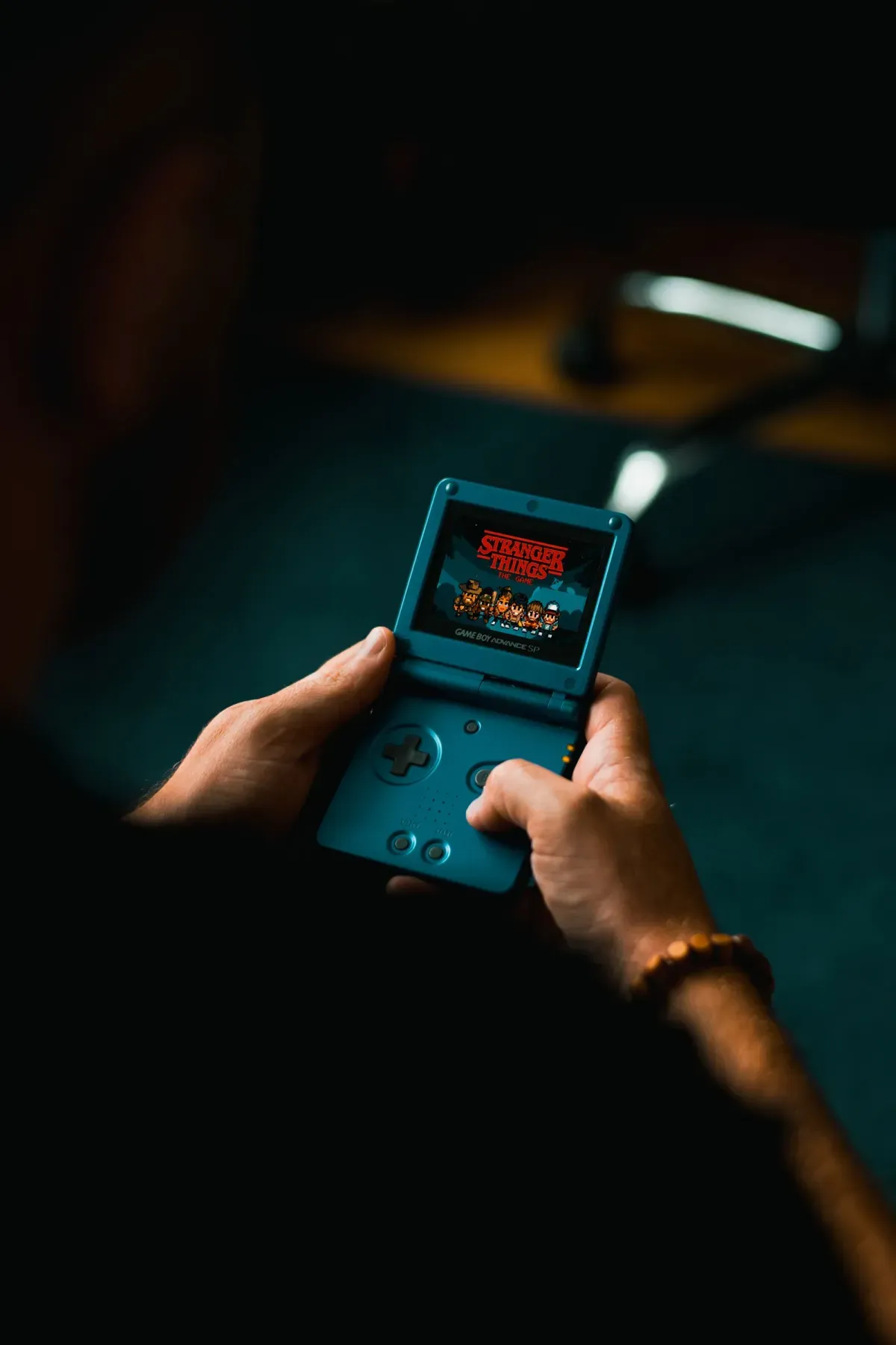 Hands holding a retro handheld virtual pet toy indoors
